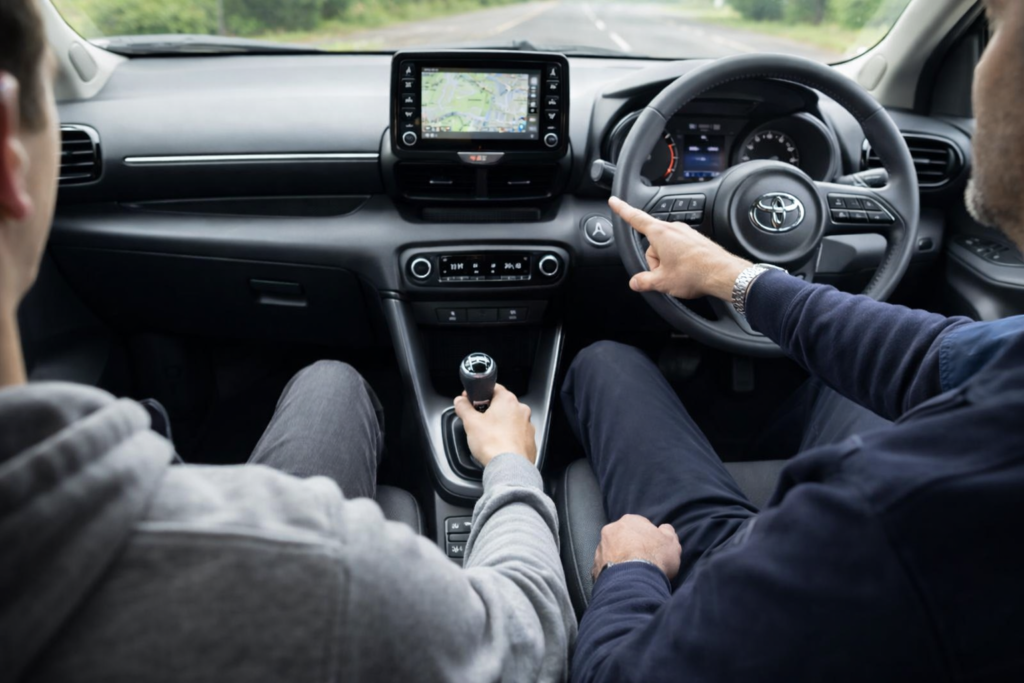 Learner driver taking a manual driving lesson inside a Toyota Yaris with instructor guidance