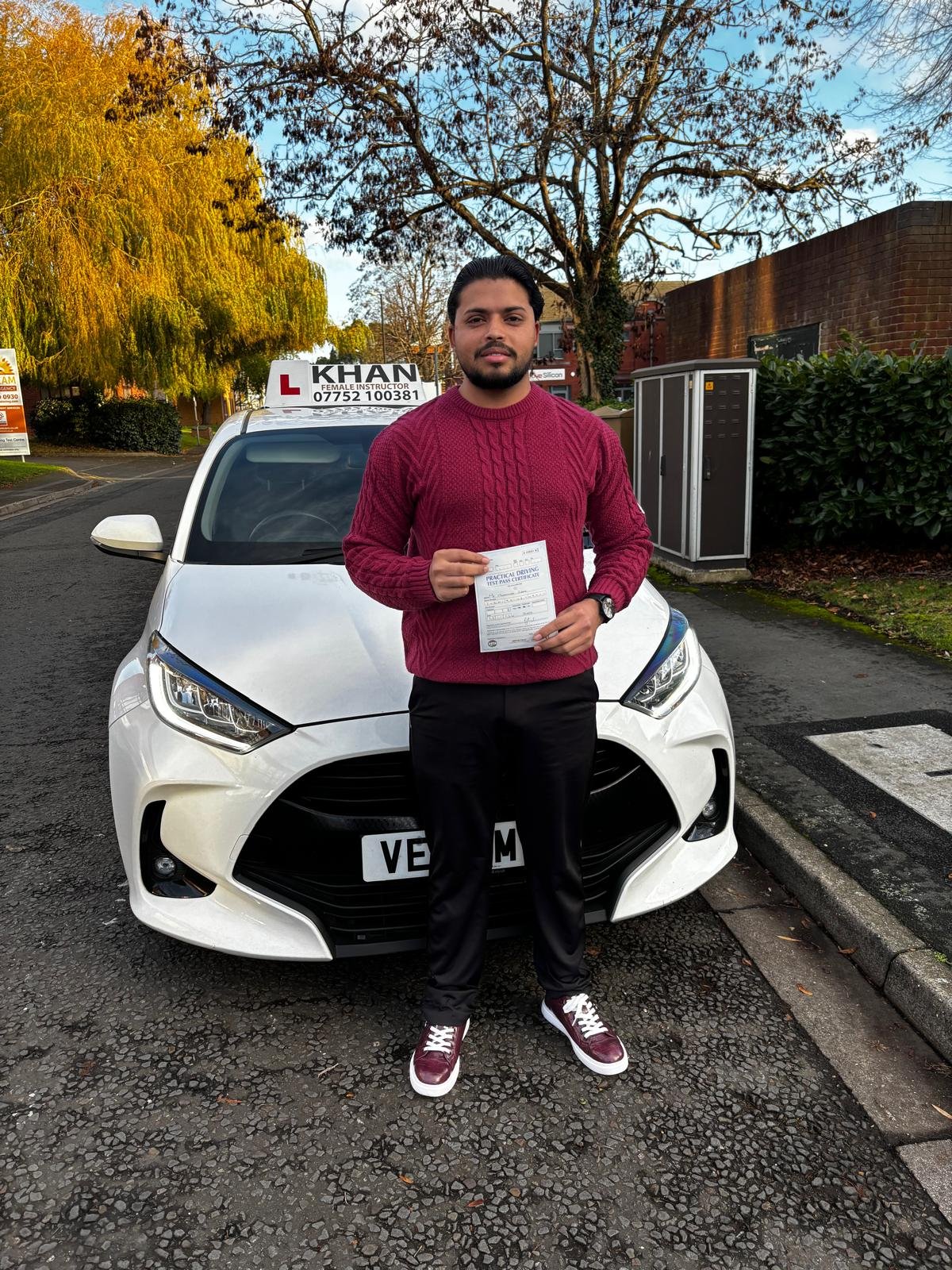 Shrican holding his driving test pass certificate next to Khan School of Motoring car in Slough