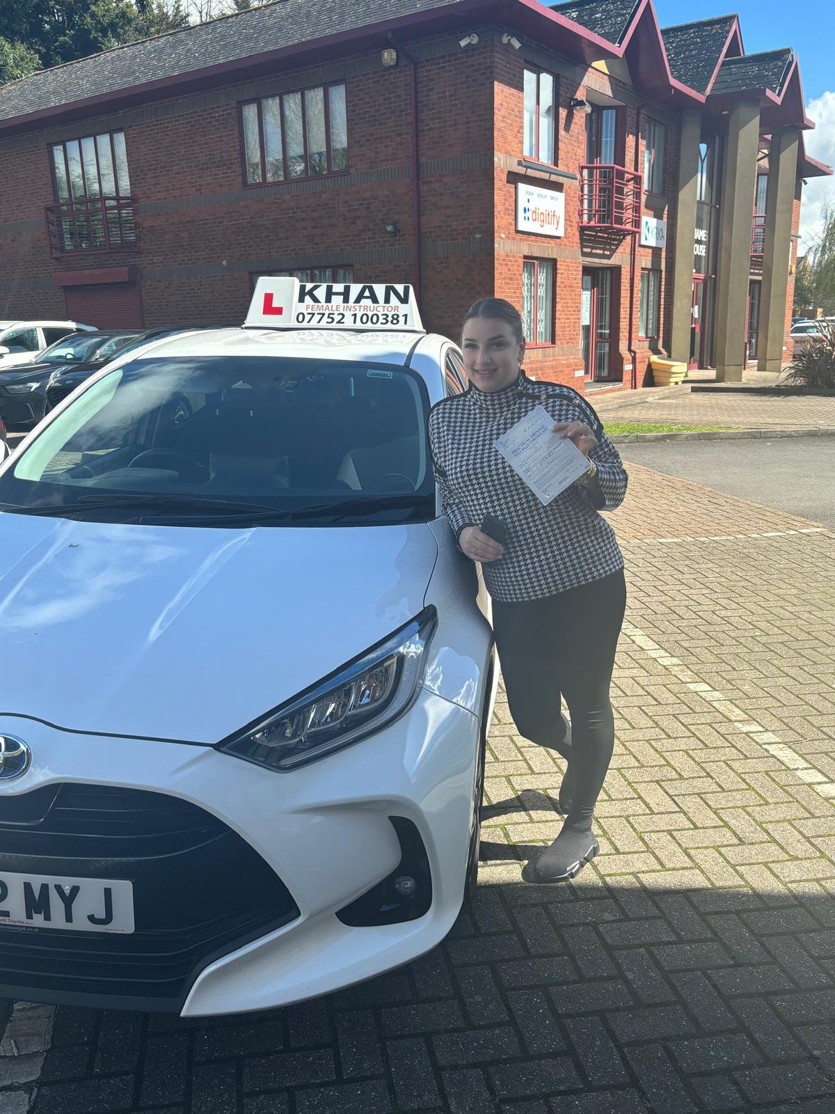Karen holding her driving test pass certificate next to Khan School of Motoring car in Slough